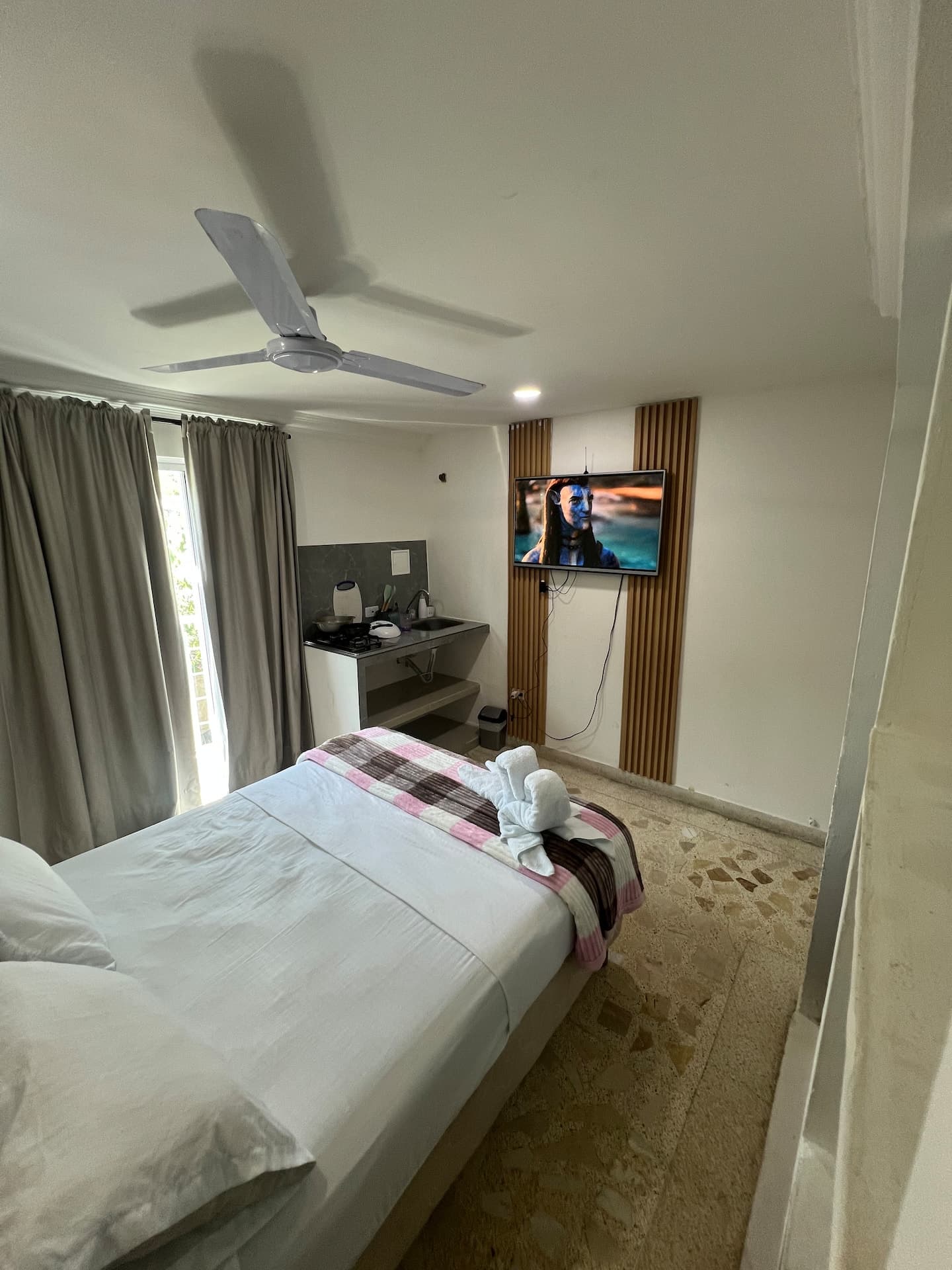Habitación con cama doble, abanico de techo y televisor