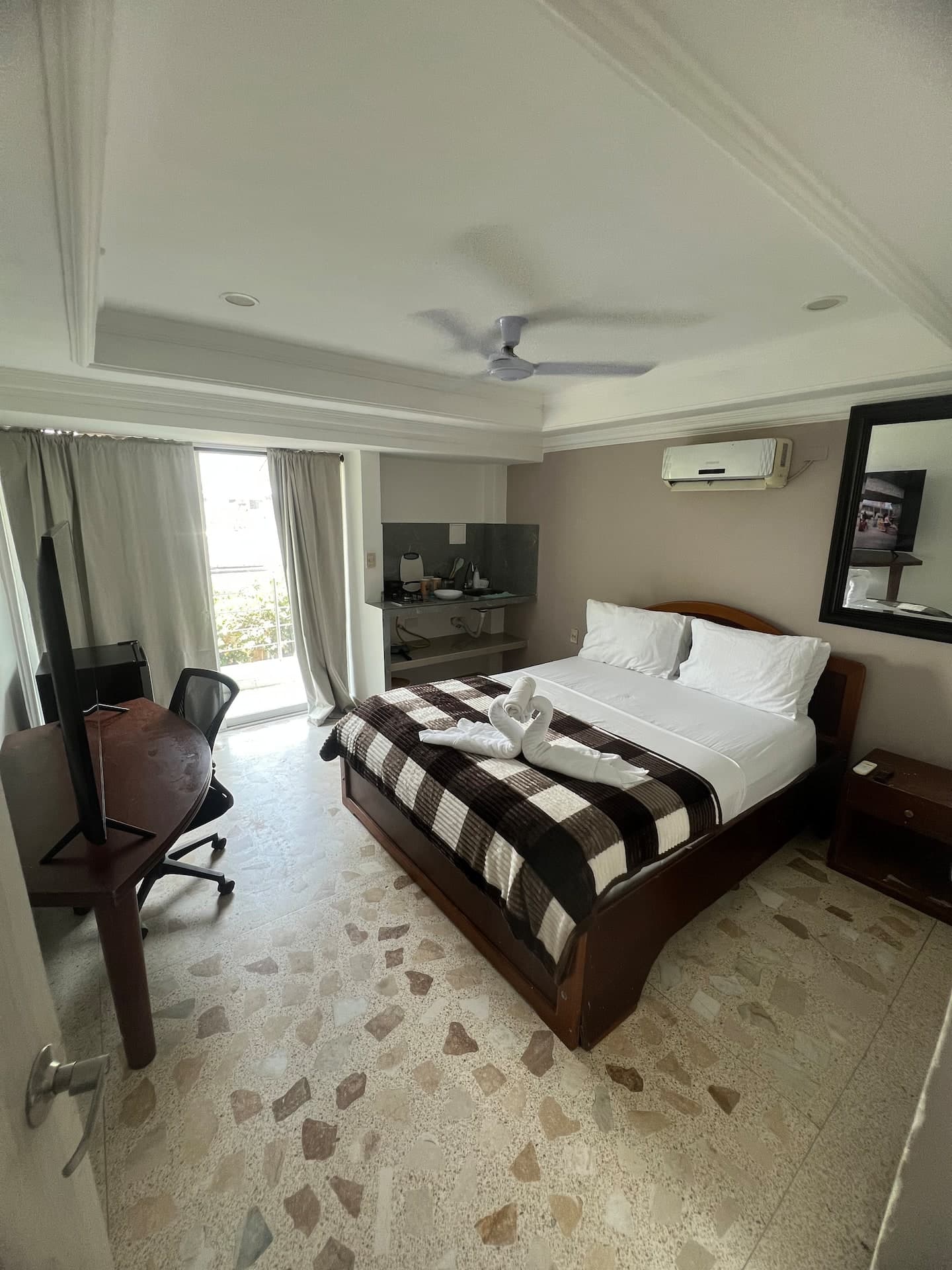 Habitación con cama doble, escritorio, cocineta y aire acondicionado